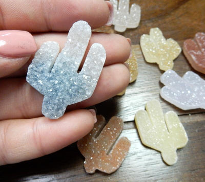 hand holding up druzy cactus cabochon with others scattered in the background