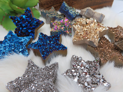 Up close view of Titanium Treated Druzy Stars displayed on fuzzy white surface.