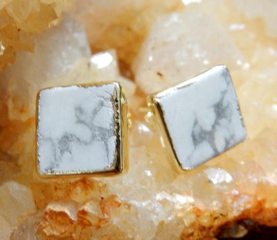 A pair of Gemstone Square Shaped Stud Earrings in White Howlite on top of a citrine cluster