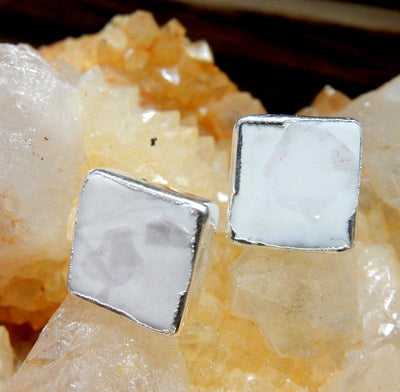 A pair of Gemstone Square Shaped Stud Earrings in White Howlite on top of a citrine cluster