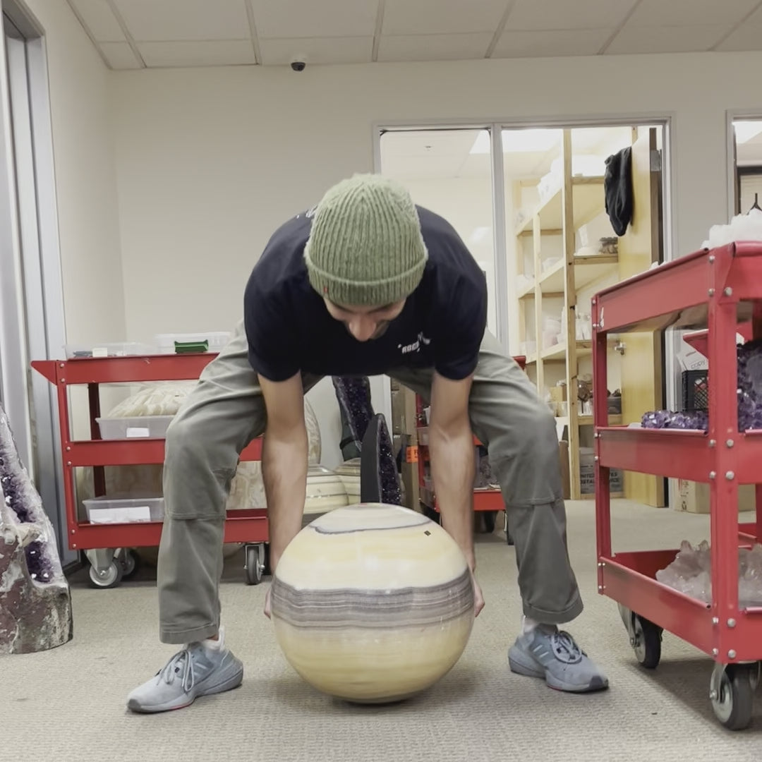 Video of man rolling Mexican Onyx - Colossal Polished Sphere Option A across carpeted floor.