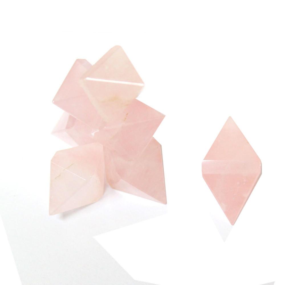 Pile of Rose Quartz Diamond Shaped Stones with one outlier on white background