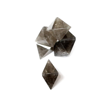 five smokey quartz diamond points ion in a pile on white background