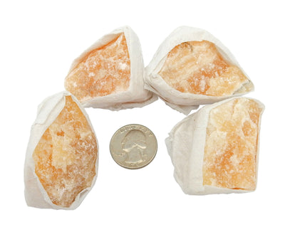 Orange Calcite pieces next to a quarter for size