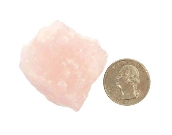 rose quartz chunk next to a quarter for size comparison on white bakcground
