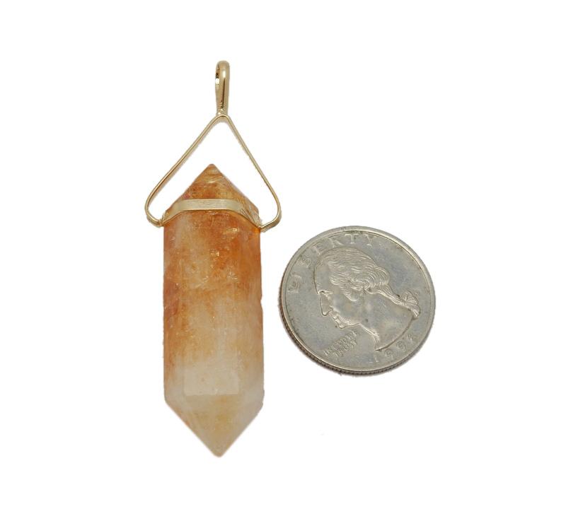 citrine point pendant next to a quarter for size reference on white background