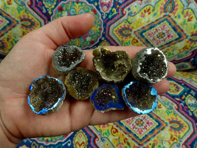 hand holding up 7 mystic half geodes in gold, platinum, and rainbow