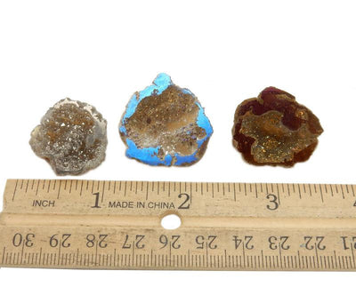 3 mystic half geodes next to a ruler for size reference on white background