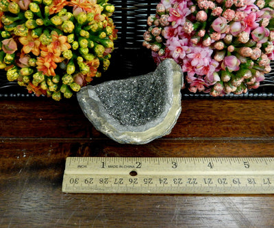platinum titanium agate druzy cluster next to a ruler for size reference with decorations in the background
