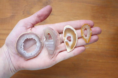 This Picture is showing geode slices displayed in a hand for size reference.