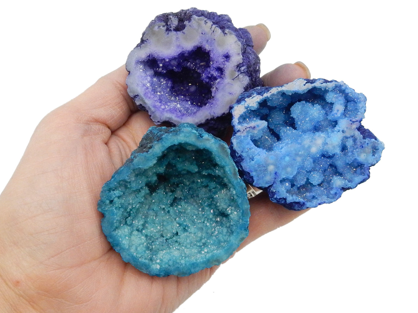 3  Large Geode Halves in a hand for size reference, in purple, blue and teal
