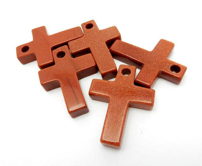 5 Goldstone red with sparkles cross on a white background.  It has a drilled hole on the top.