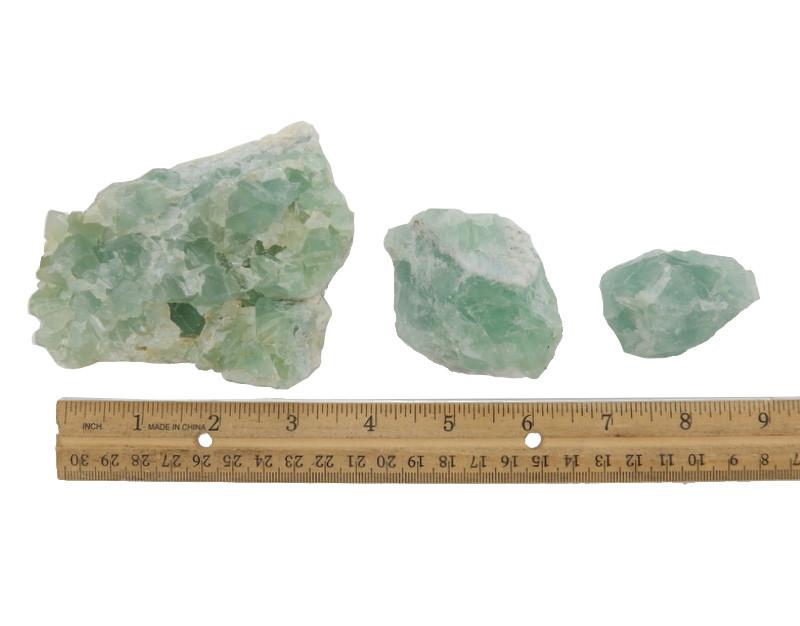 Three Green Fluorite crystals in different sizes next to ruler to show size comparison