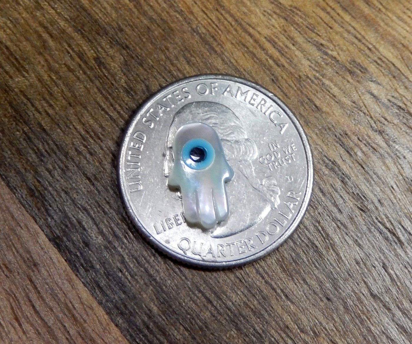Single Petite Mother of Pearl Hamsa Hand with Eye Accent on top of a quarter for size comparison 