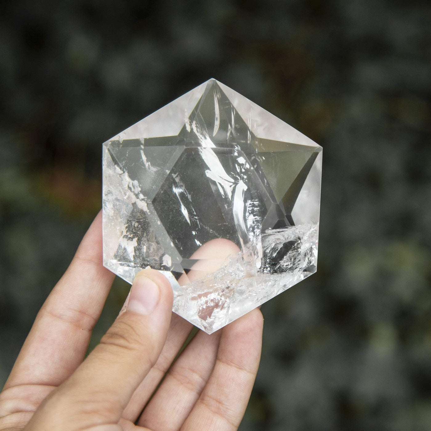 hand holding up crystal quartz hexagonal pocket stone in front of dark background