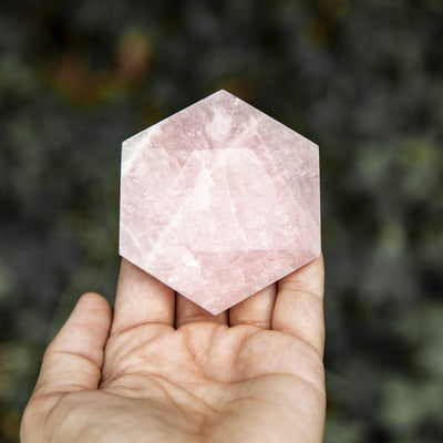 hexagonal rose quartz polished stone in hand for size reference 