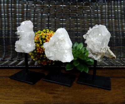 Three Crystal Quartz Cluster on metal stand, displayed on a wooden surface.
