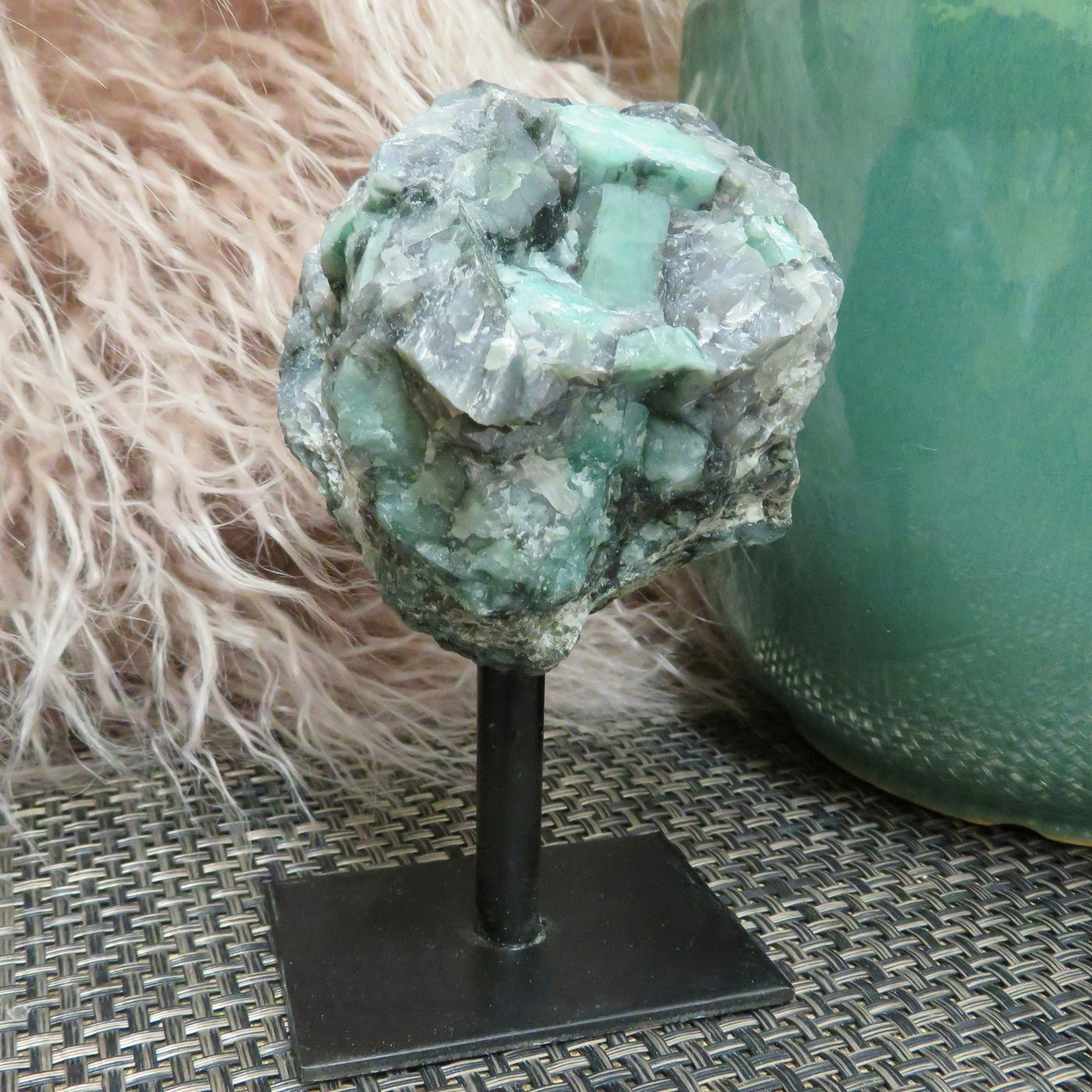 A single Emerald on metal Stand with a green and brown background 
