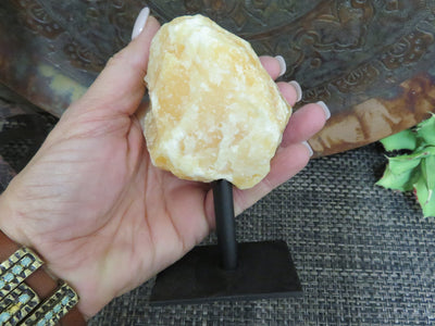 Products Orange Calcite on Metal Stand - in a hand