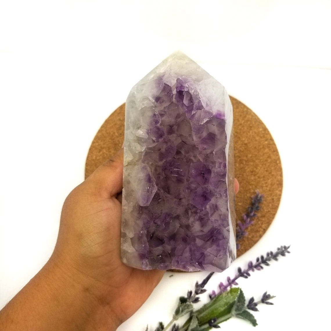 hand holding up Amethyst Polished Geode Crystal Cut Base Cluster with decorations in the background