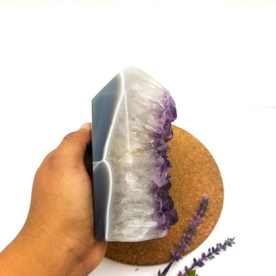 hand holding up Amethyst Polished Geode Crystal Cut Base Cluster with decorations in the background