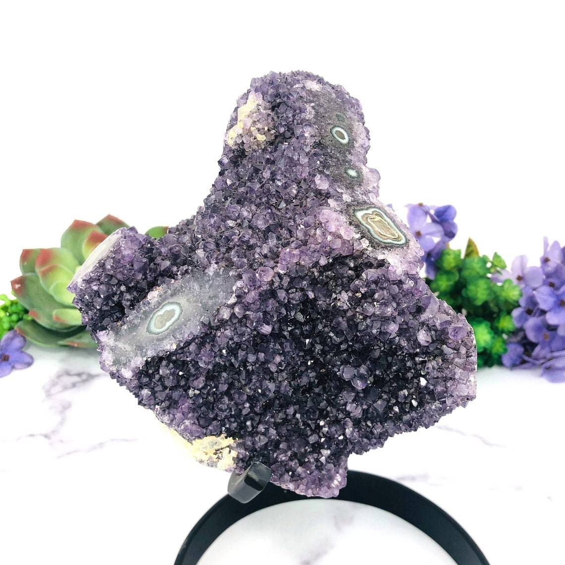 Amethyst Purple Geode Crystal With Stalactite on Metal Stand with decorations in the background