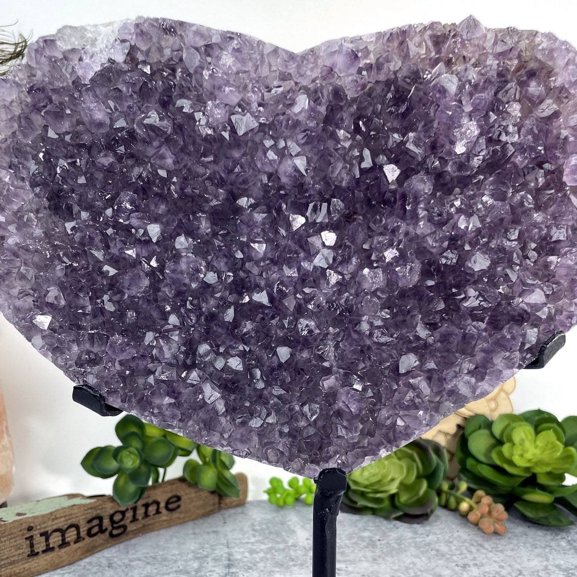 up close shot of Amethyst Druzy Heart On Metal Stand with decorations in the background