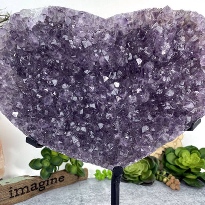 up close shot of Amethyst Druzy Heart On Metal Stand with decorations in the background