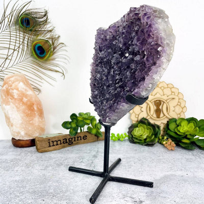 side view of Amethyst Druzy Heart On Metal Stand with decorations in the background