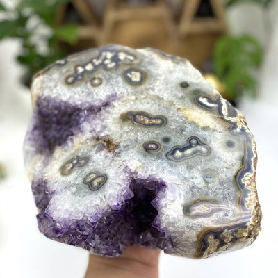 Amethyst piece with white stalactite formations all over it in a woman's hand.