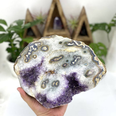 Amethyst piece with white stalactite formations all over it in a woman's hand.