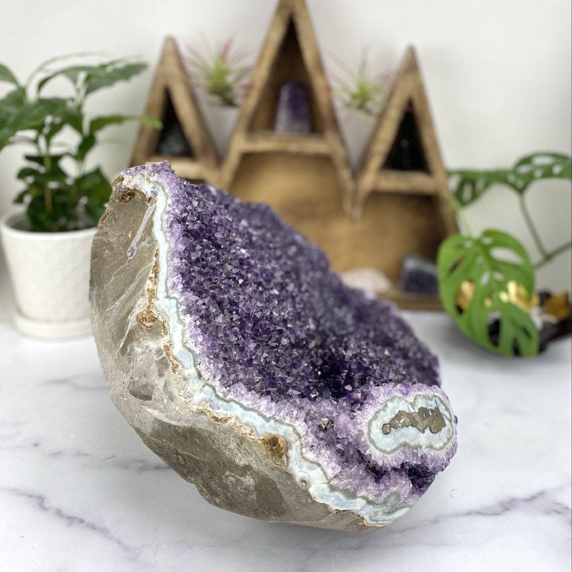 side view of Amethyst Cluster with a Stalactite with Calcite with decorations in the background