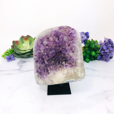 Amethyst Purple Geode Crystal on Metal Stand  with decorations in the background