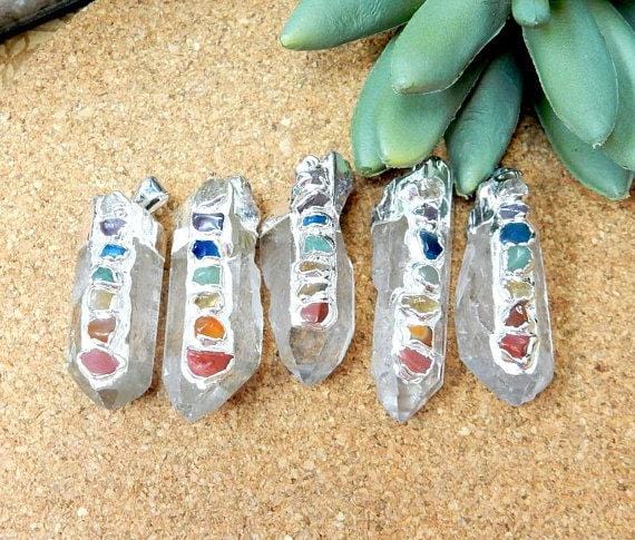 5 silver Crystal Quartz Point Pendants on brown background