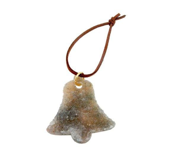 druzy quartz cut into a bell shape and strung on a brown cord to make an ornament.
