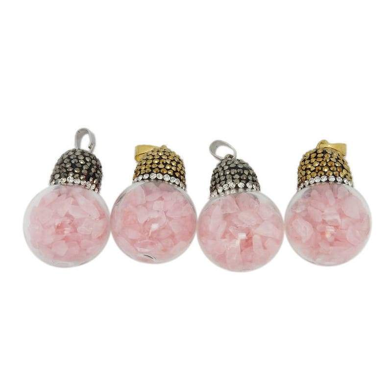 An assortment of pendants with glass balls filled with rose quartz chips on a white background.
