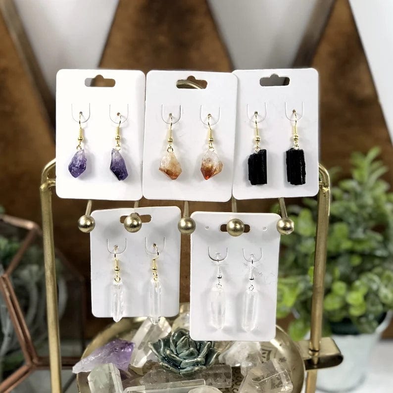 All stones available pictured on white hang tag cards.  Pictured amethyst point earrings with gold plated ear wires, citrine point earrings with gold plated ear wires, black tourmaline earrings with gold plated ear wires, crystal point earrings with gold plated ear wires, and crystal point earrings with silver plated ear wires.