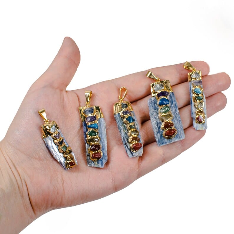 Raw Blue Kyanite Chakra Pendants Charms with gold plating in a hand for size reference