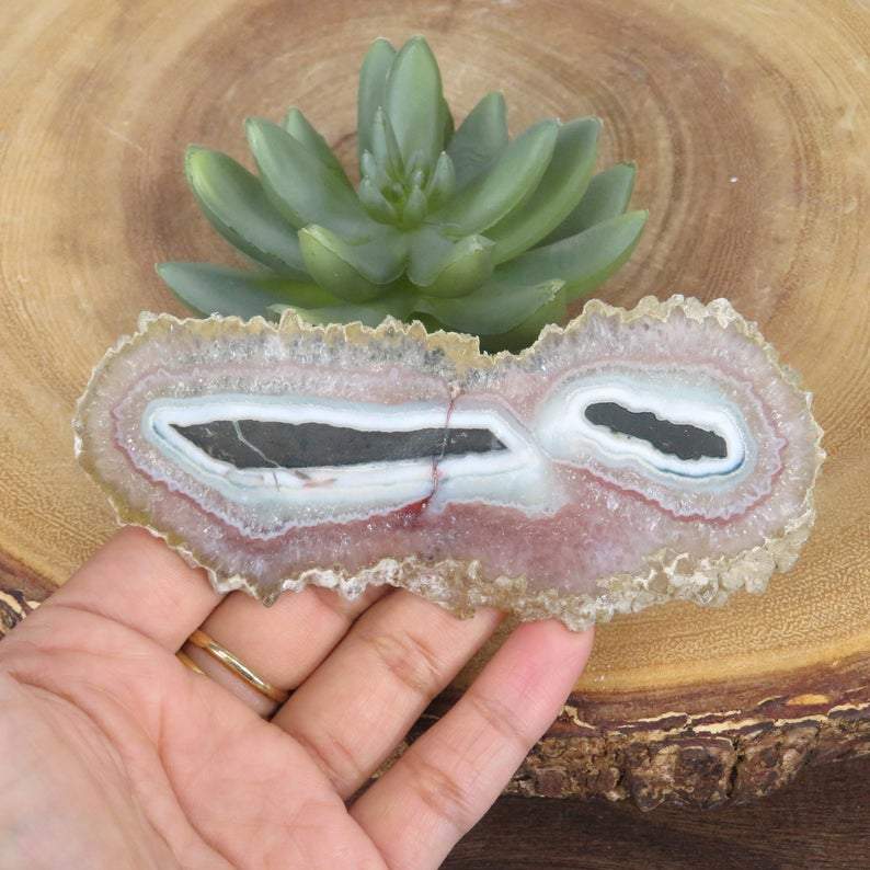 hand holding Light Amethyst Stalactite with decorations in the background