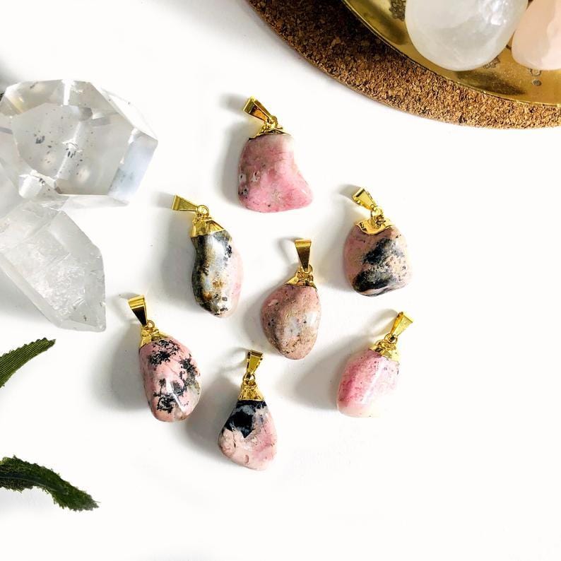 7 Rhodonite Tumbled Pendants with other crystals on  white background