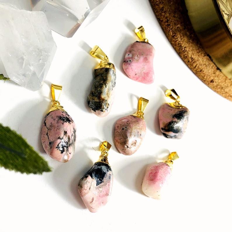 Rhodonite Tumbled Pendants with other crystals and decorations in the background