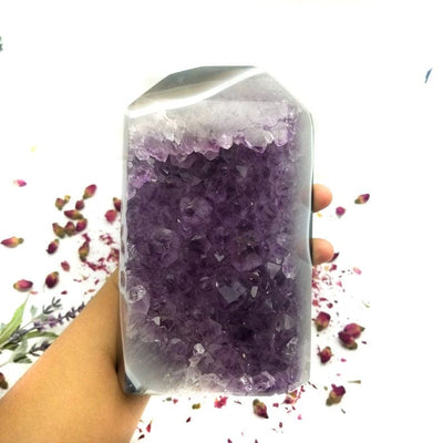 Amethyst Crystal Cut Base in Hand with decorations in the background