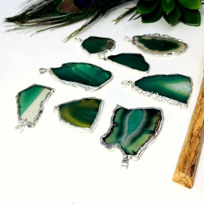multiple freeform green agate pendants displayed side view for thickness reference