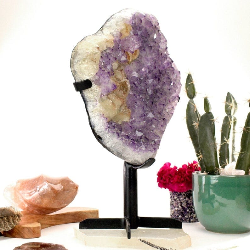 angled shot of Amethyst Crystal Purple Geode on Metal Stand with decorations