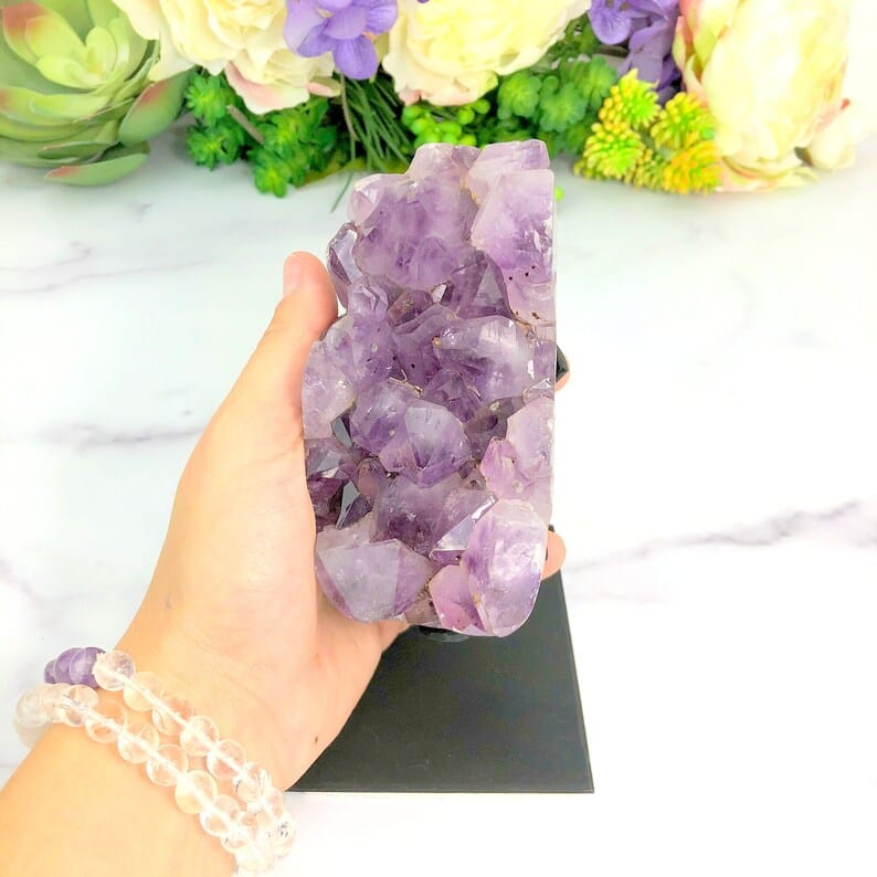 Amethyst Crystal Purple Geode on Metal Stand with a hand for size reference