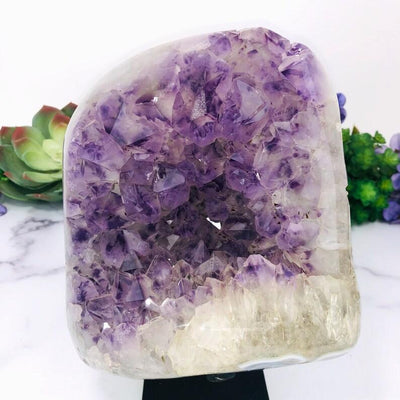 up close shot of Amethyst Purple Geode Crystal on Metal Stand  with decorations in the background