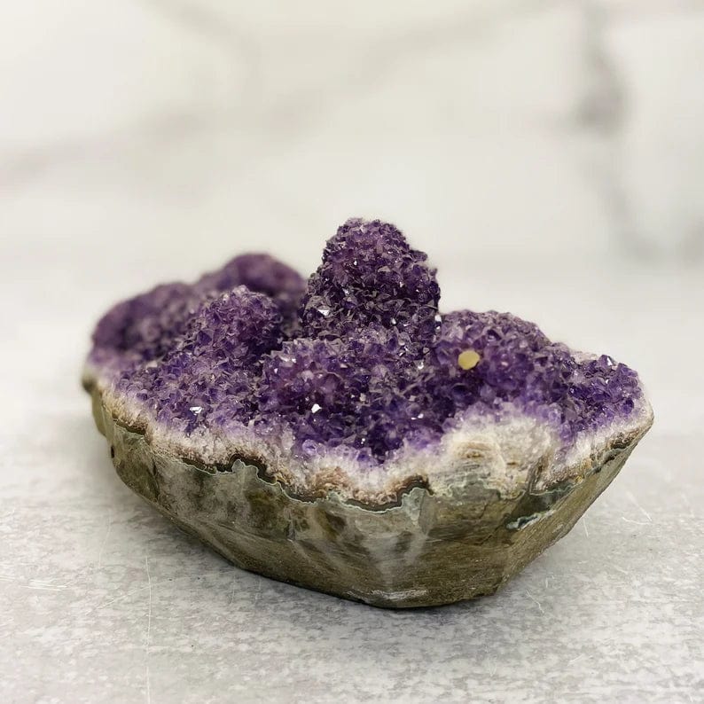 Side view of amethyst cluster.  Large amethyst cluster formation with basalt bottom.  This piece is purple clusters on top and gray with green on bottom basalt layer.