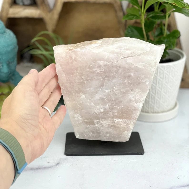 Rose Quartz on Metal Stand next to hand for size comparison