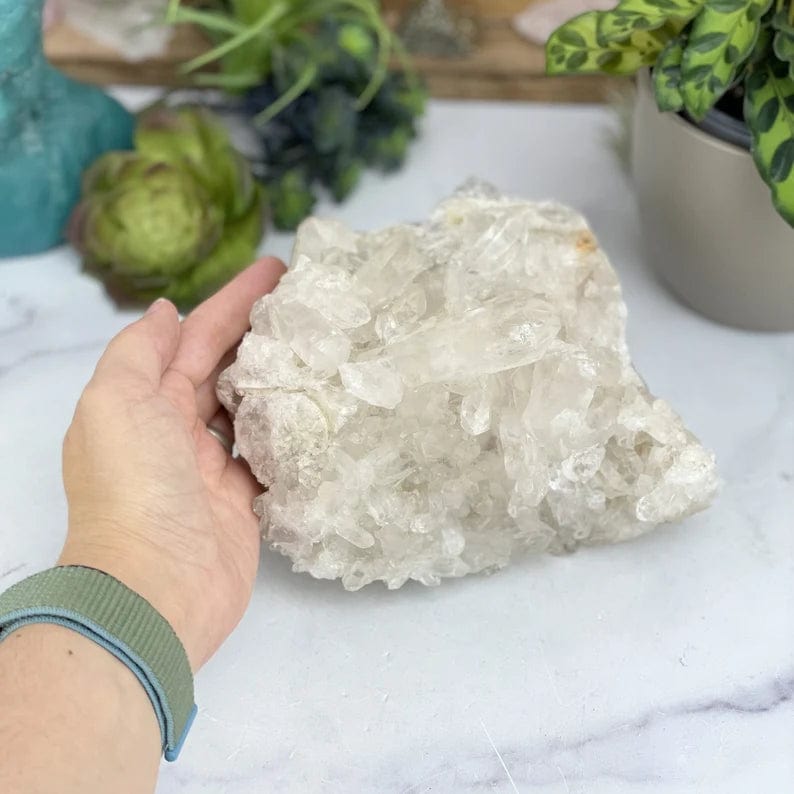 Large Raw Crystal cluster on display with a hand for size reference
