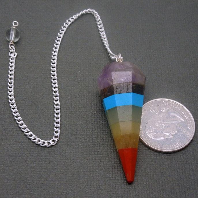 close up of one seven chakra point pendulum with silver plated chain with quarter for size reference